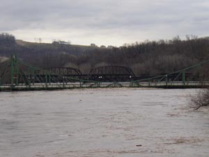 A river hits the bottom of a large bridge.