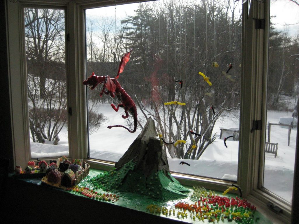A candy red dragon flies over a large mountain. Below, gummy bear warriors prepare to fight.