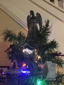 A close-up of the geek tree topper: the Weeping Angel from Dr. Who. The angel is about 8 inches tall, with a grey body, wings, and hands covering her face.