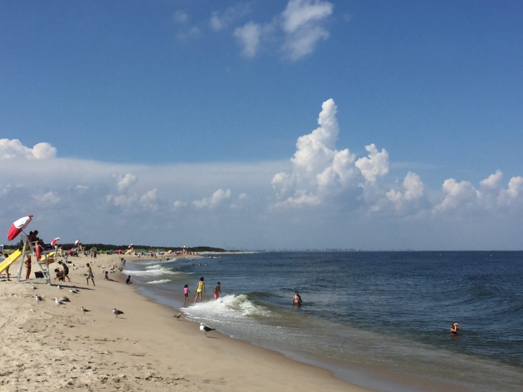 A picture of the New Jersey shore, with the beach and a lifeguard stand to the left and the ocean to the right. In the far distance the New York City skyline can be seen.