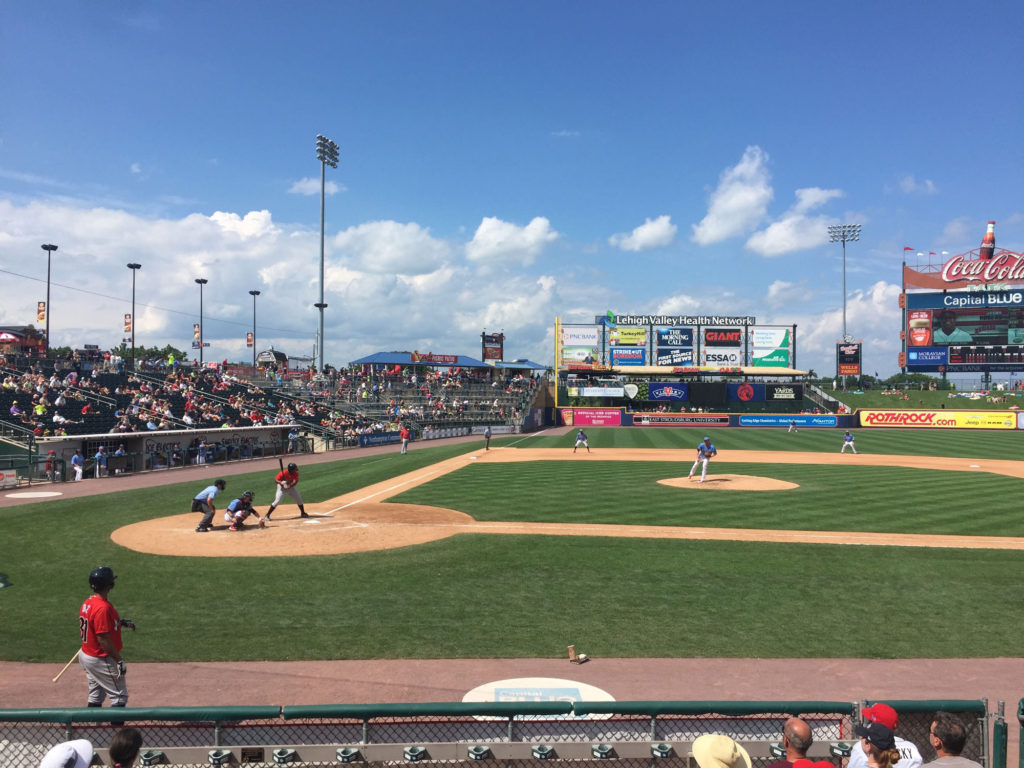 A minor league baseball team plays a game on a beautiful, mostly-sunny summer day.