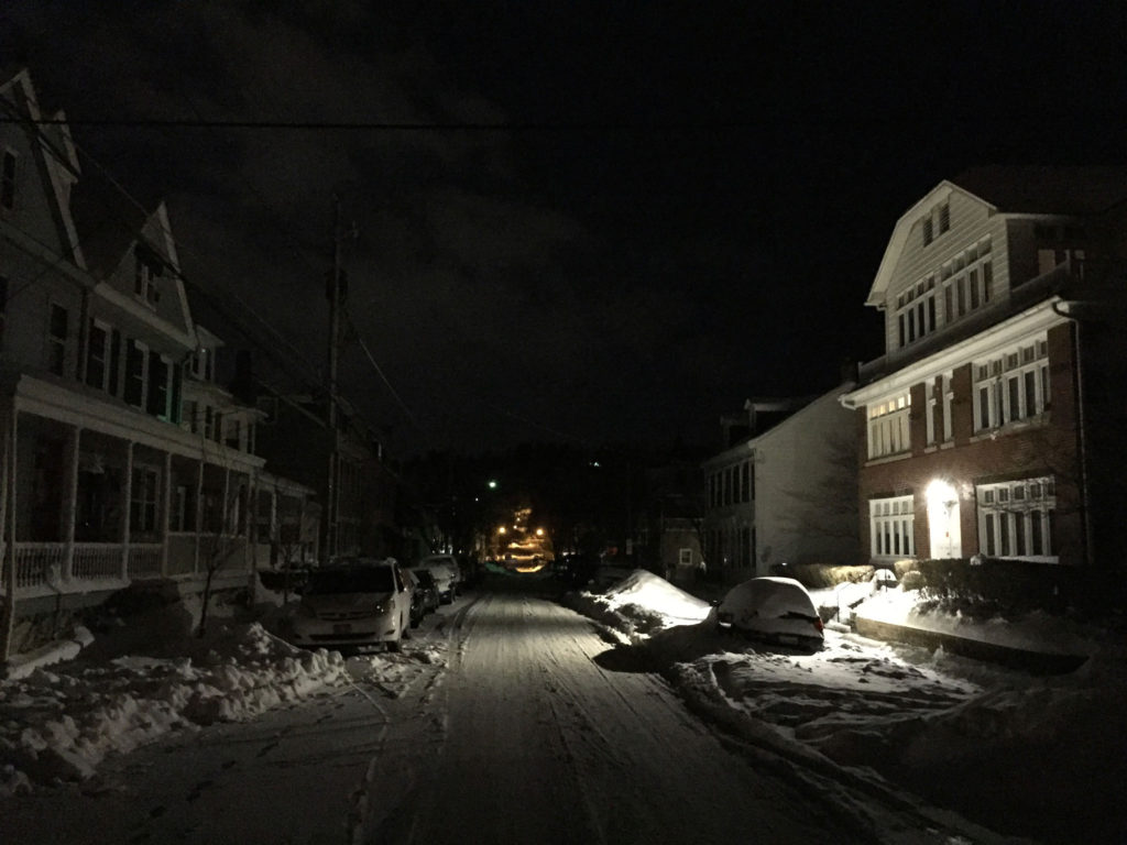 Streetlights illuminate a snowy street.