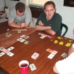 A group of male gamers plays a non-collectible card game.