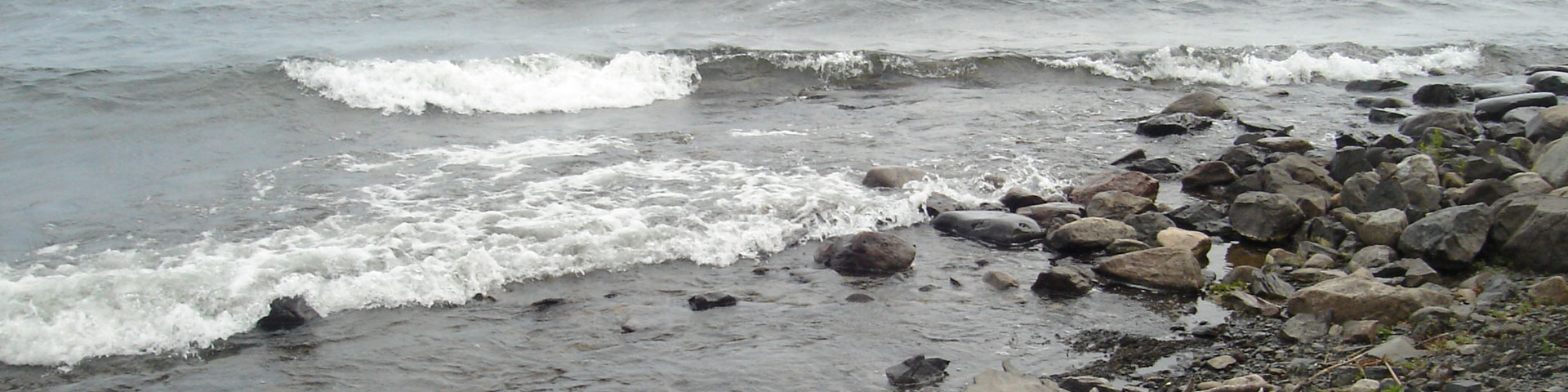 Waves rush in toward a stony shore.