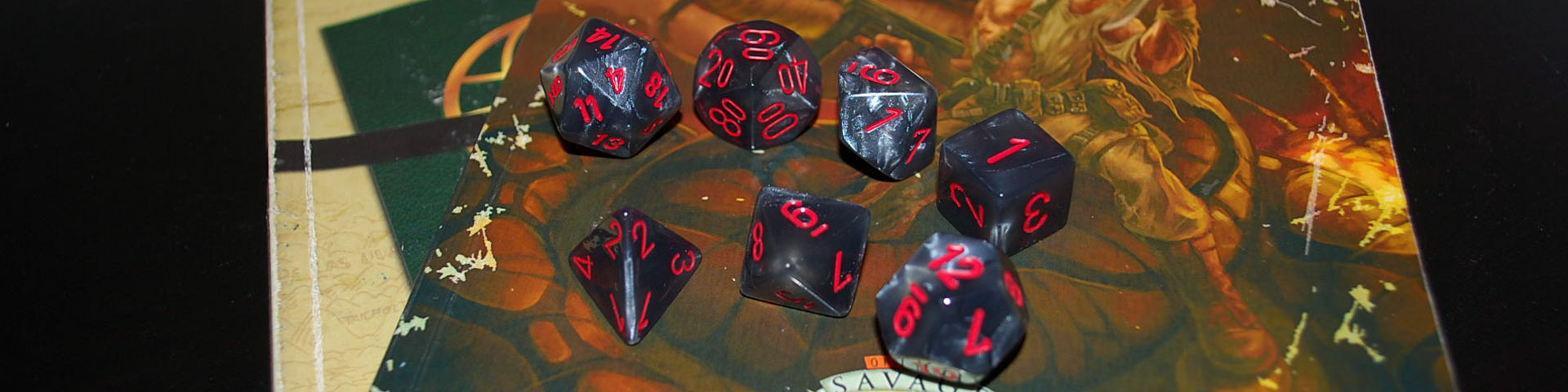 Black and grey dice with red numbers sit on top of role-playing game source books.