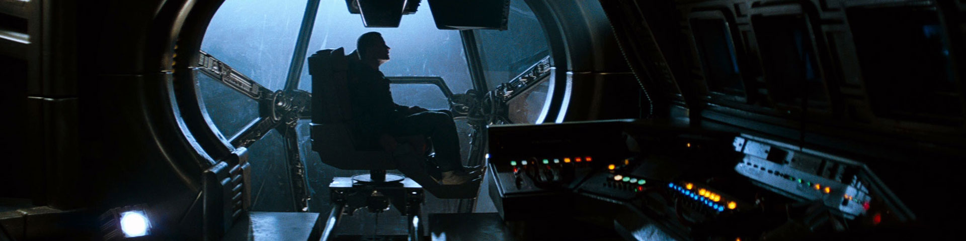 A lone individual sits in an observation bubble on a starship, surrounded by dingy, beat-up computer equipment.