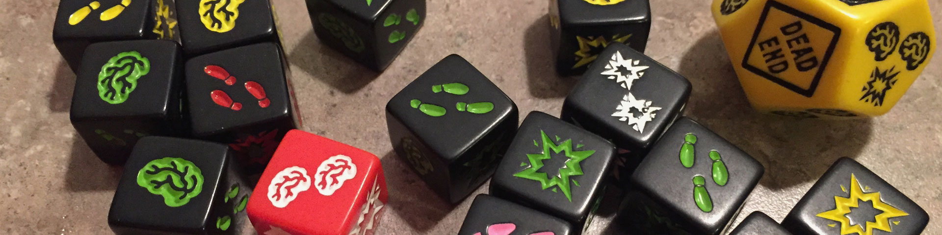 Black and red dice feature one of three symbols: brains, footprints, or shotgun blast. A larger yellow die has "dead end" printed on it.