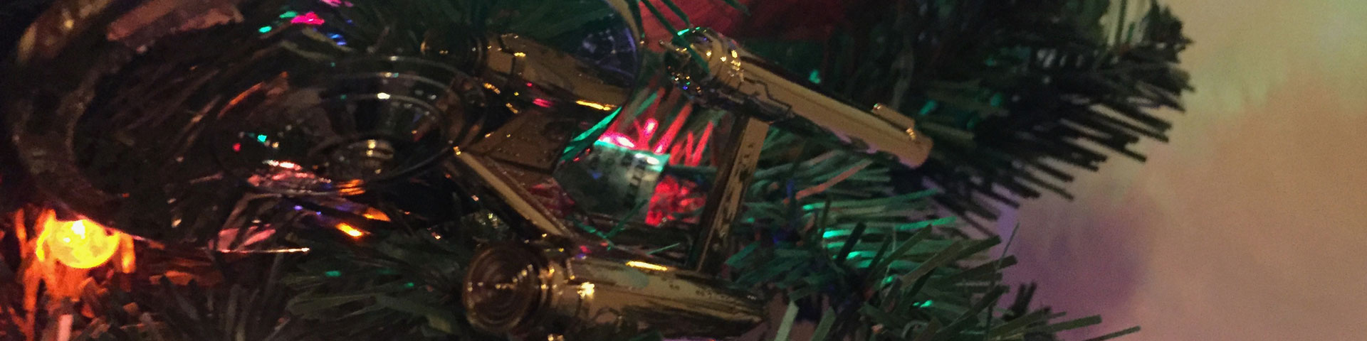 A golden starship reflects nearby Christmas lights as it hangs on an artificial tree.