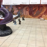 A large purple worm towers over several hero miniatures on a battle map.