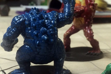 Plastic miniatures of the frog-like monsters known as slaadi stand on a battlemap. In the background can be seen several figures representing player characters.