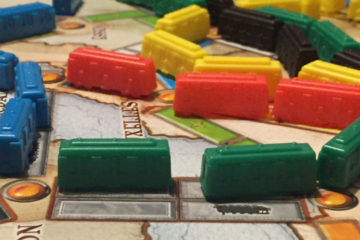 Multi-colored train pieces represent different routes that have been completed on the Ticket to Ride map.