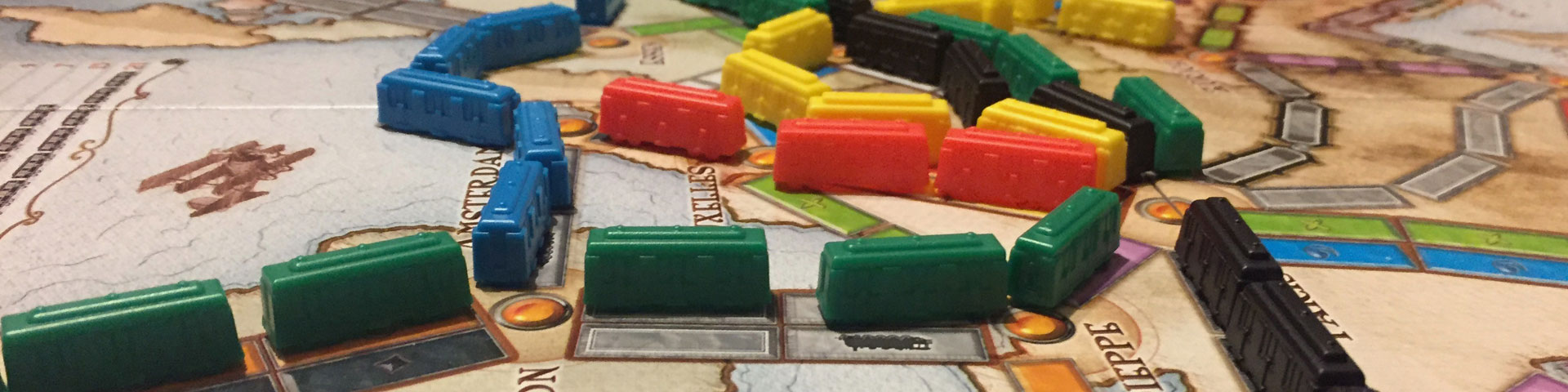 Multi-colored train pieces represent different routes that have been completed on the Ticket to Ride map.