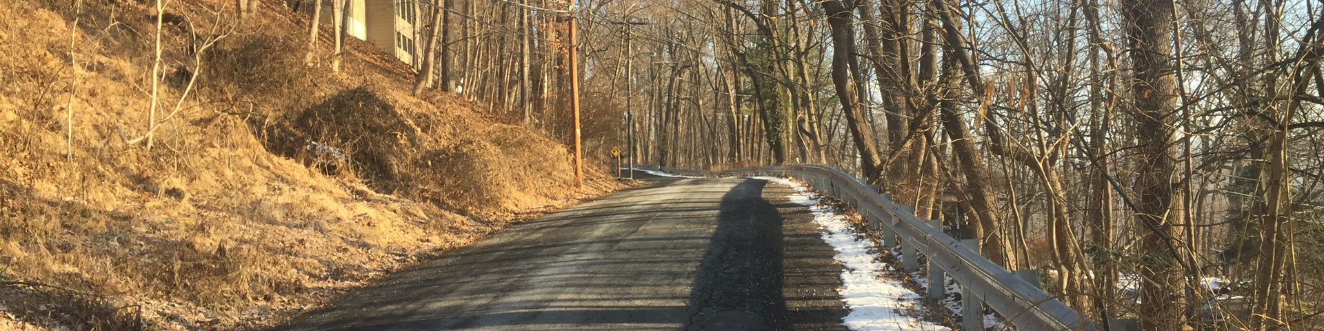 A back country road, with a thin line of snow on the right shoulder.