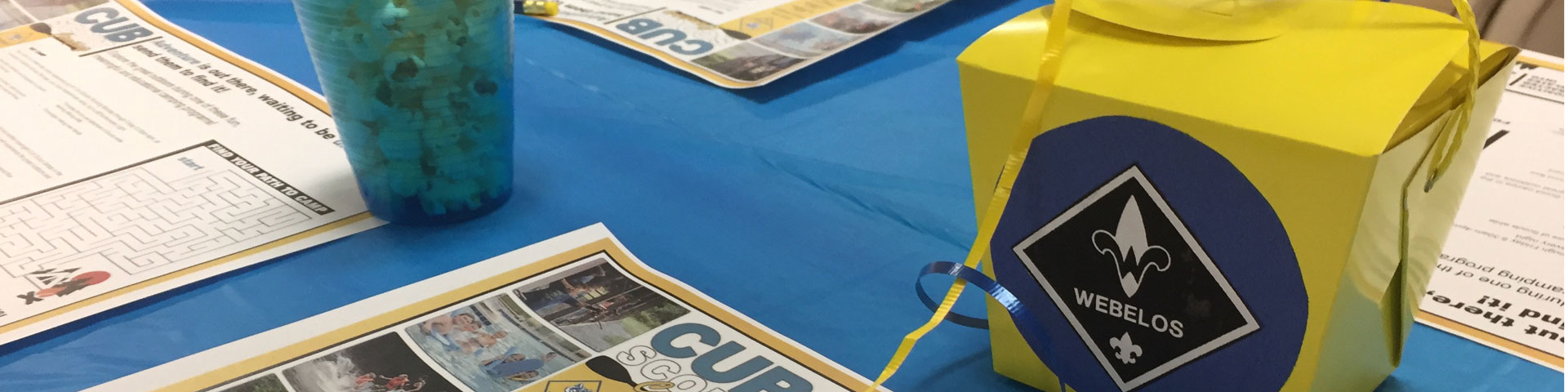 An activity worksheet and a yellow box stand against a blue table cloth