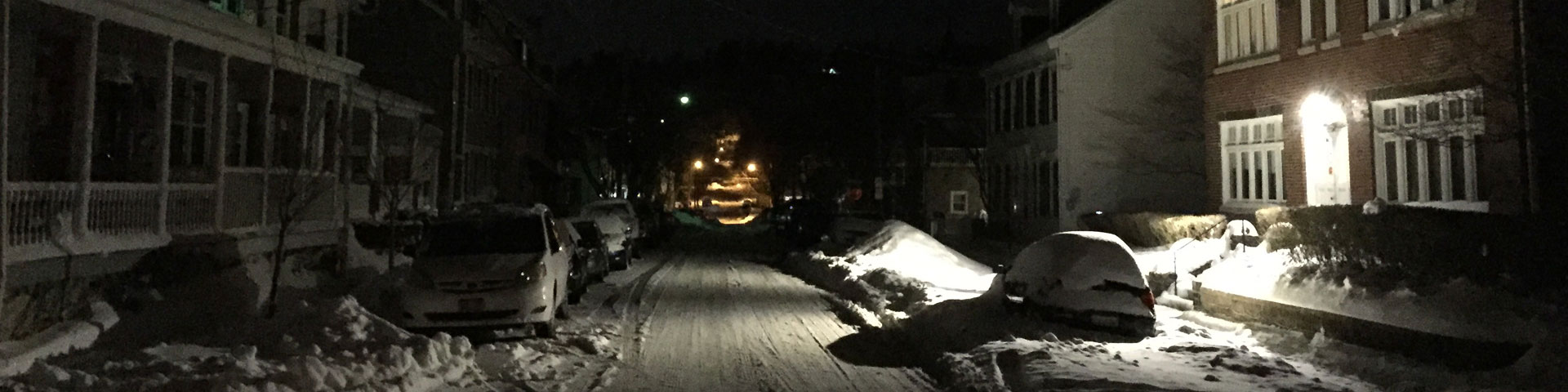 Streetlights illuminate a snowy street.