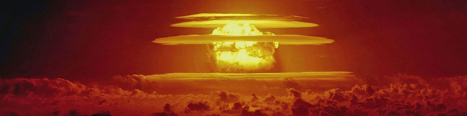 A nuclear mushroom cloud rises through the atmosphere, glowing yellow against the orange sky.