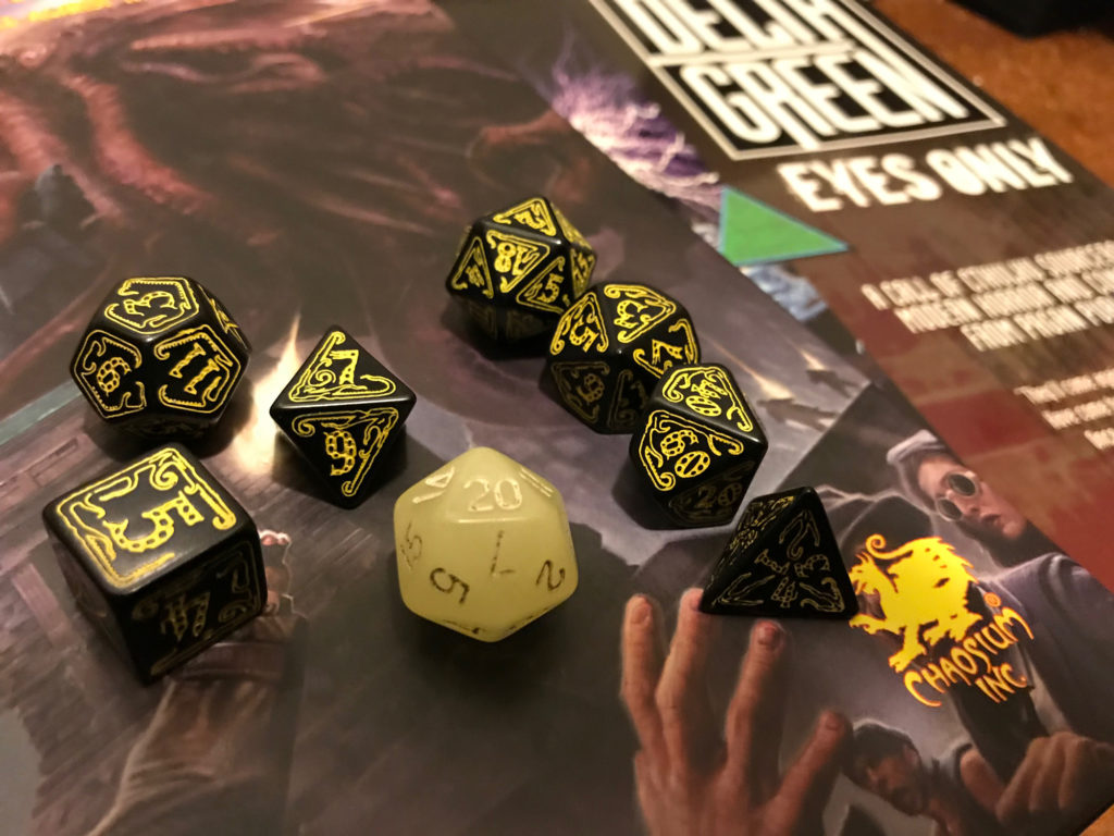 Black dice with yellow lettering appear on role-playing book covers. A single yellow-ish glow-in-dark d20 amid them.