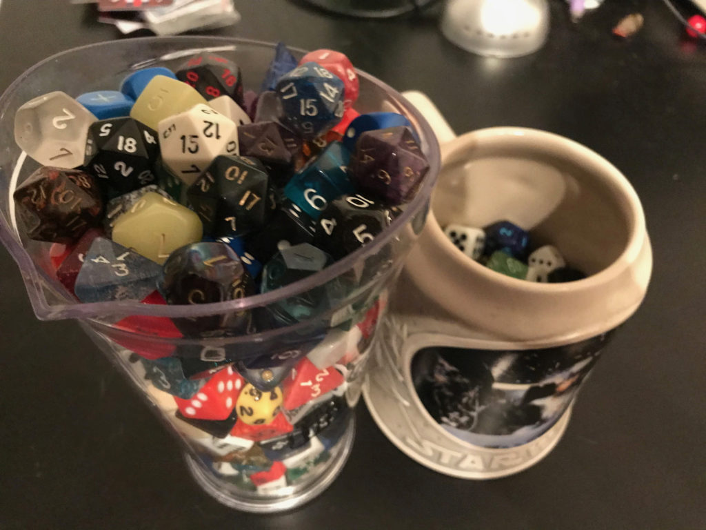 A large plastic pitcher and a ceramic mug filled with dice.