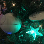 The sphere of the Death Star appears to the left; the starship Enterprise to the right. A glowing blue star is seen beneath them.