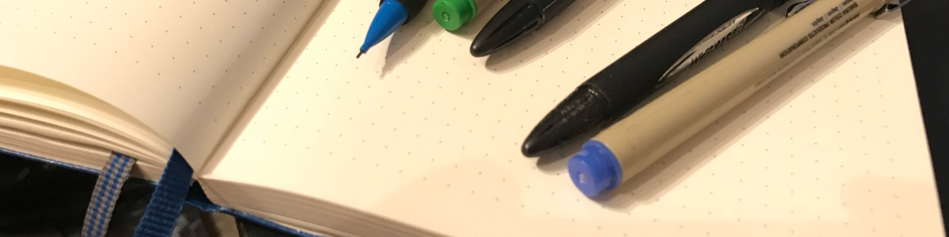 Pens and pencils atop a writing journal.