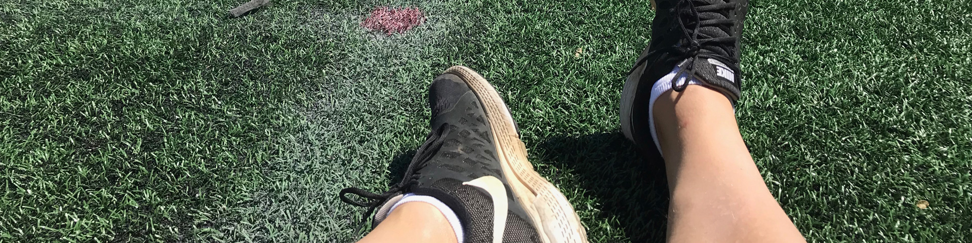 My be-sneakered feet resting on a field.