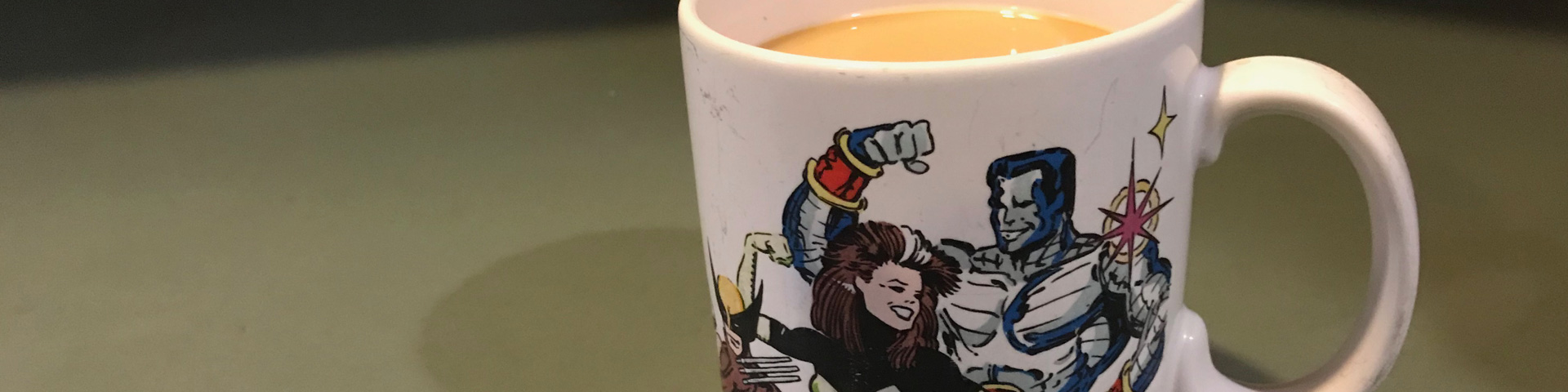 A coffee cup featuring the X-men appears on a green counter top.