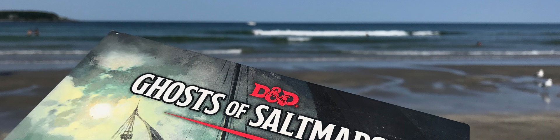 The cover of the Ghosts of the Saltmarsh RPG book appears in front of the ocean.