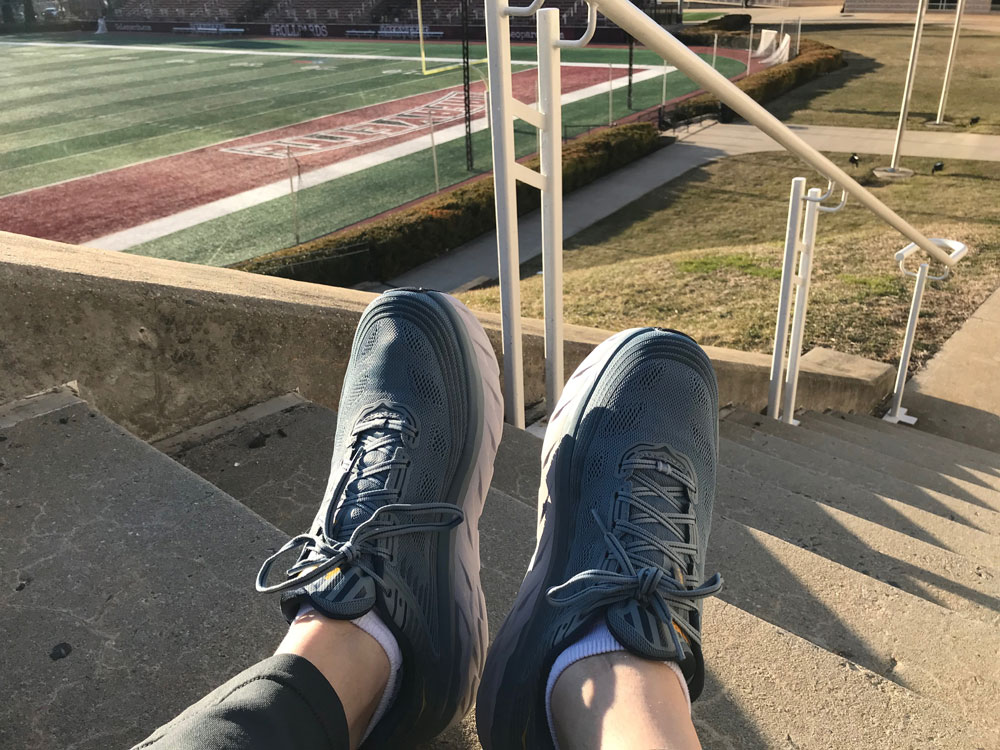 A photo of grey sneakers taken on a staircase. A football field appears in the background.