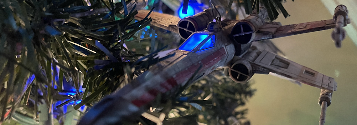 An X-Wing Fighter in a Christmas Tree. The cockpit glows blue.