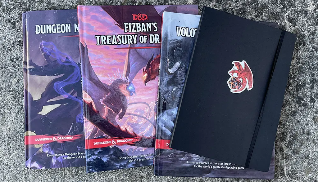 A collection of Dungeons and Dragons rule books, as well as a black notebook with a dragon logo.