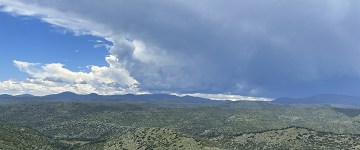 A distant mountain range with blue skies competing with massive clouds.